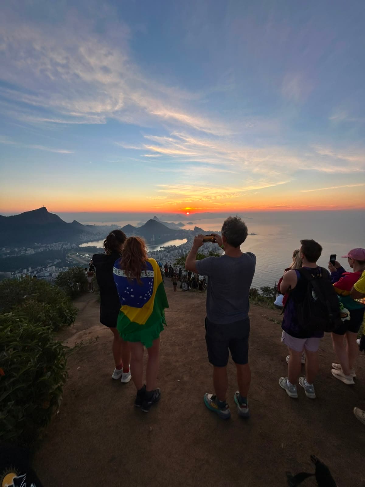 Turistas fotografando o nascer do sol no topo da trilha